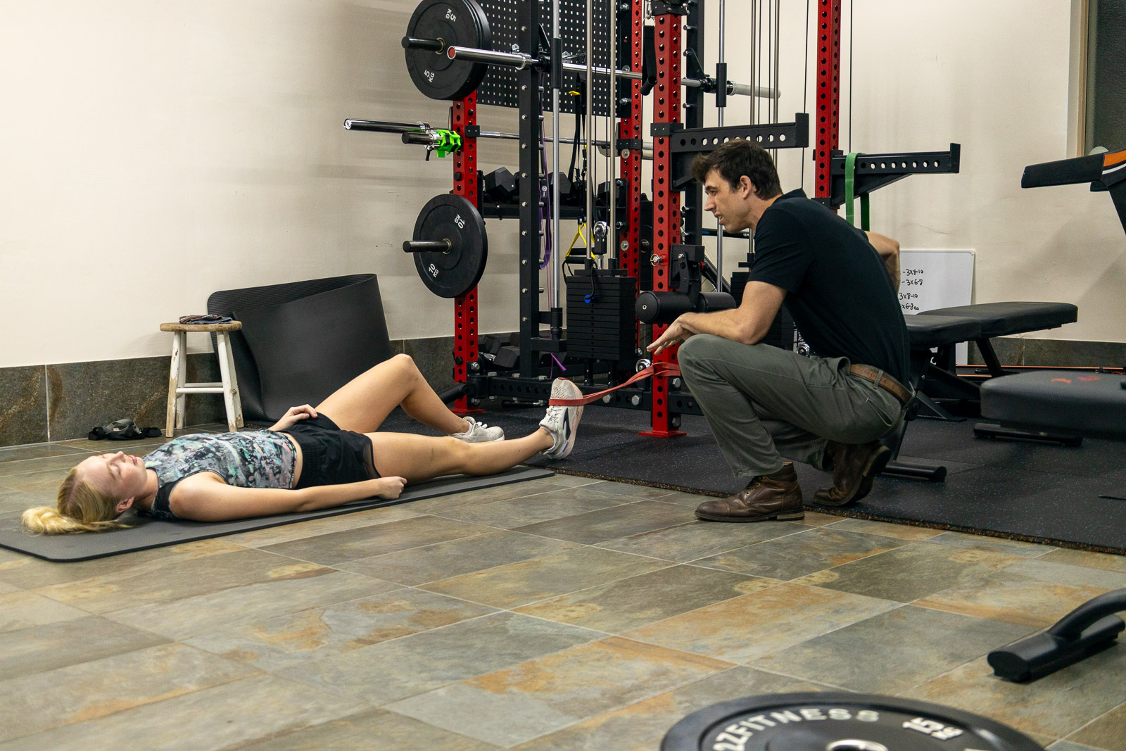 Exercise Physiologist supervising a client during a lower limb resistance exercise.