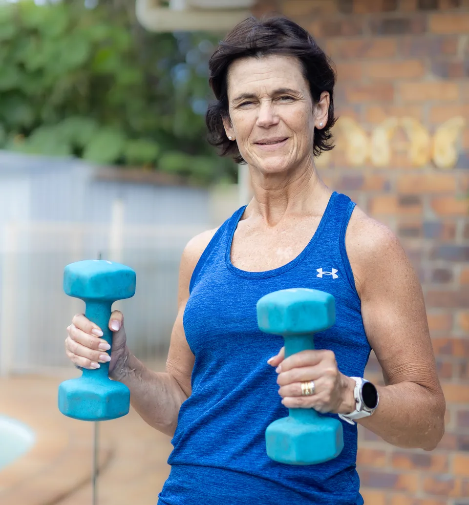 A woman holding dumbbells for strength exercise at home